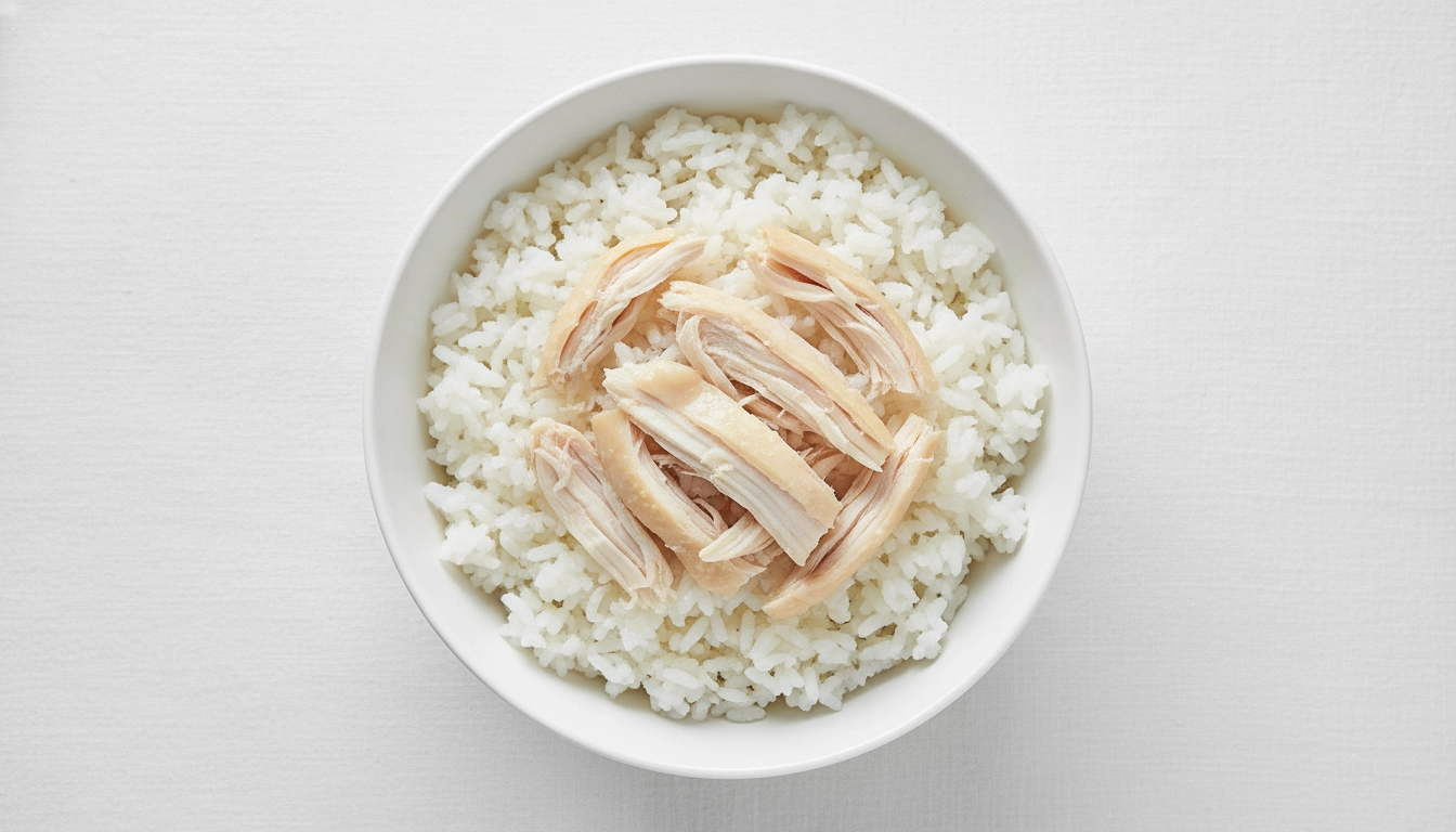 A bowl containing shredded boiled chicken and plain white rice.